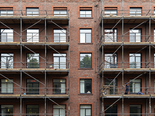 Construction site with scaffolding installation in urban environment, showing professional team working with equipment and safety measures in place