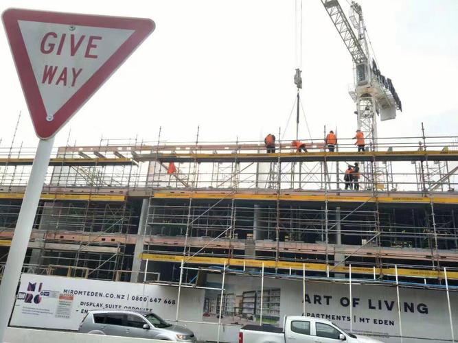 Modern scaffolding equipment in professional setting with blue sky background, showing organized rental facility with various types of scaffolding materials stacked neatly
